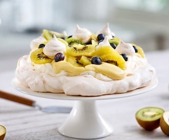 Pavlova med gul og grønn kiwi, blåbær og appelsin